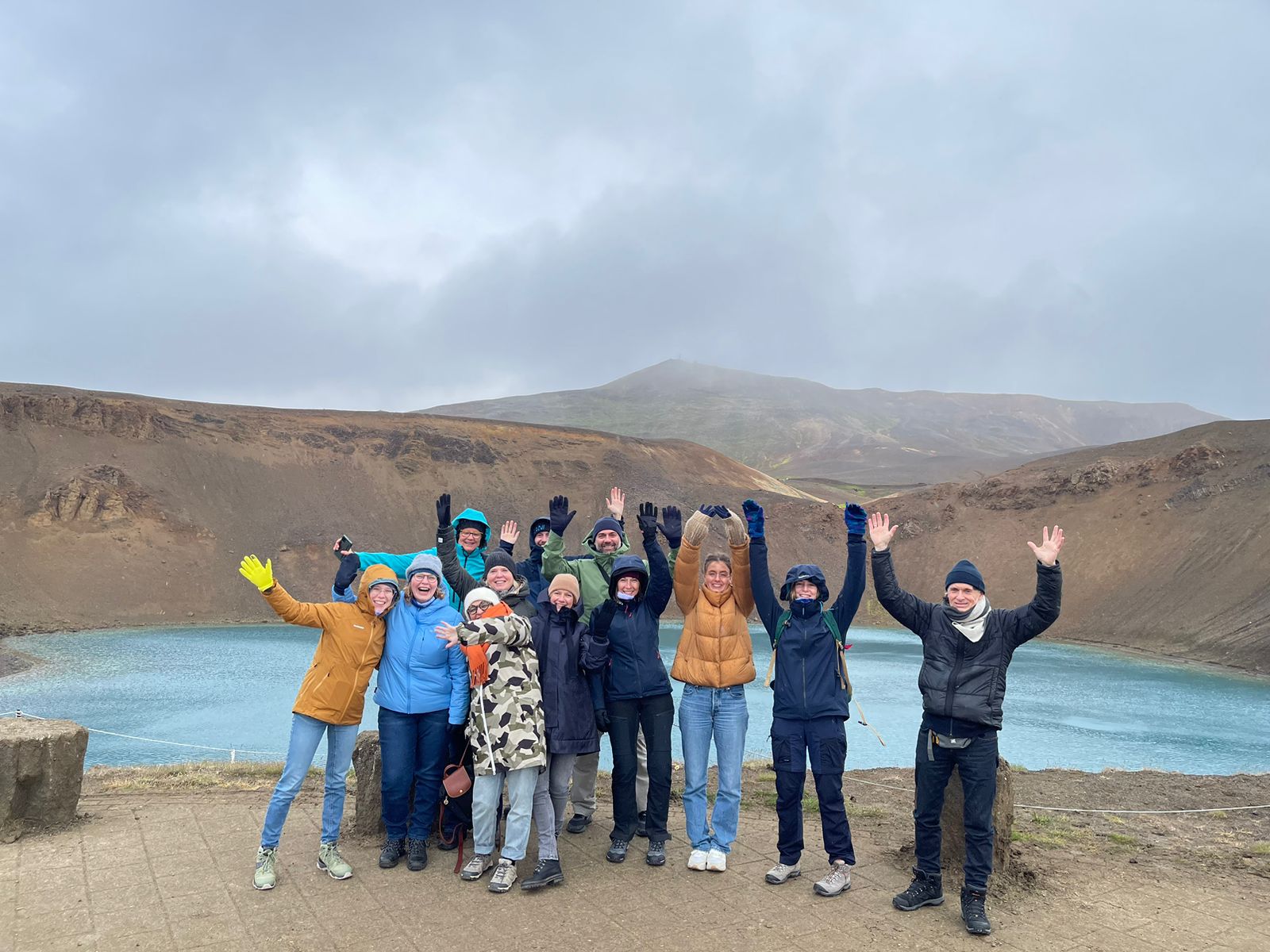 ICEBERG project members hands raised above with a mountain in the background.