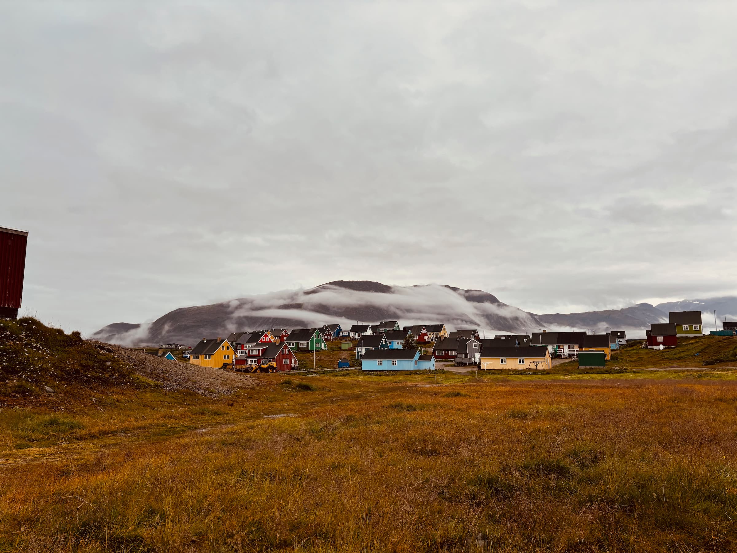 Views of Narsaq, Greenland, on a rainy day. Colourful houses and mountains in the background.