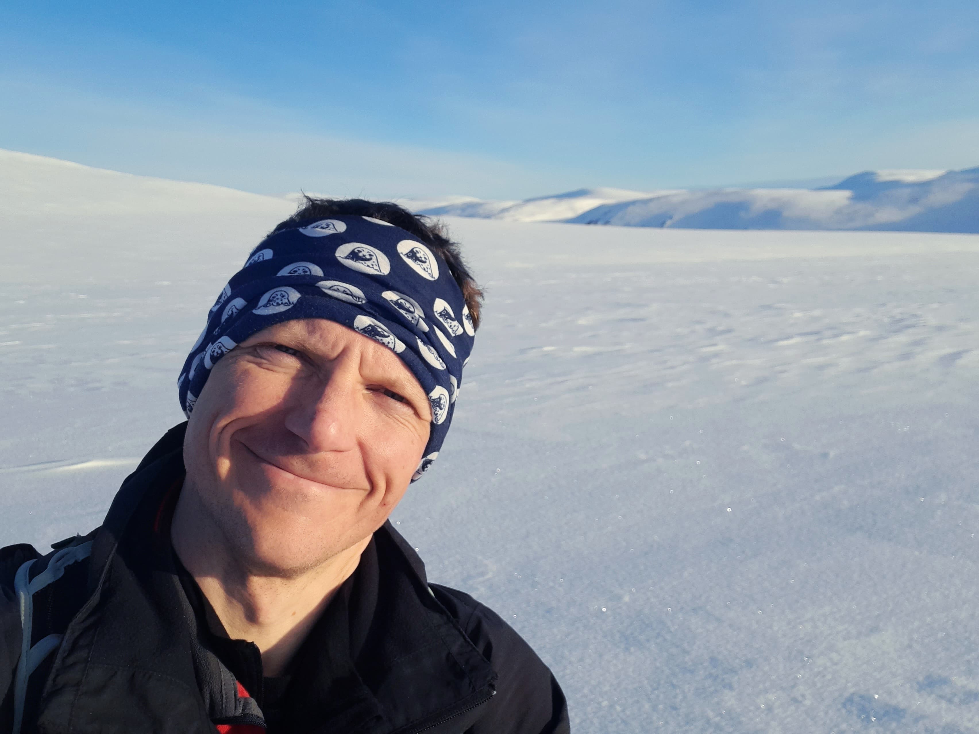 On a selfie taken in a snowy landscape, Adam Stepien poses for the camera.