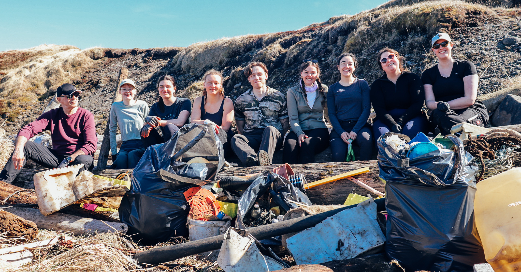 Volunteers on a rocky beach in Iceland posing behind a huge pile of plastic items found from the beach.