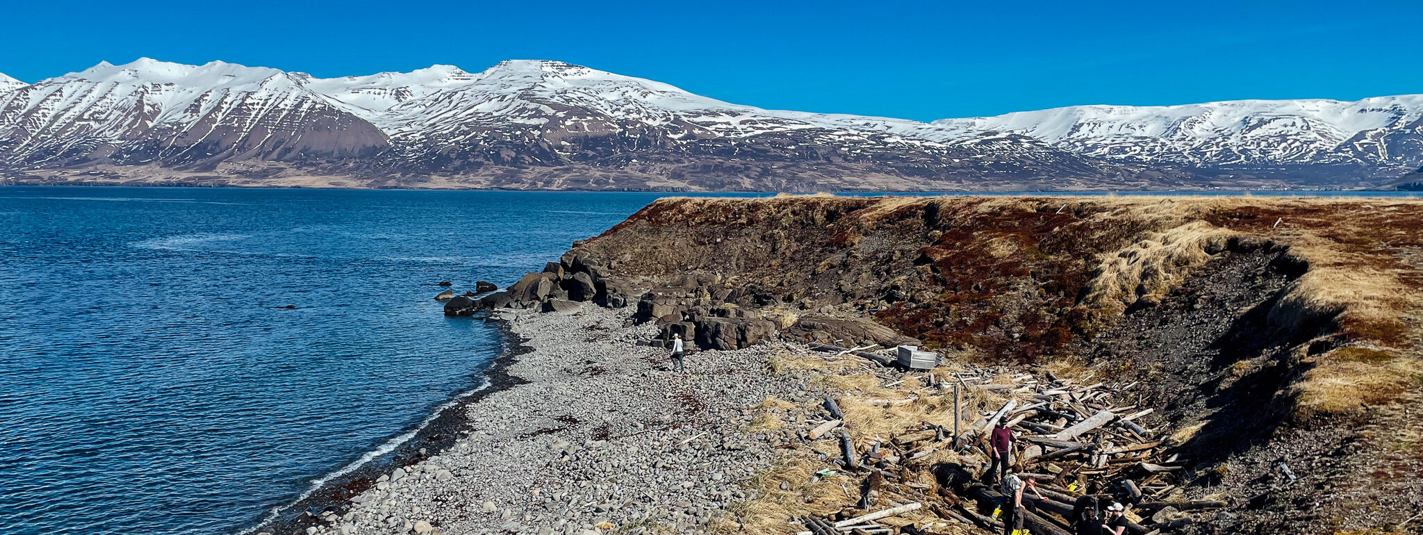 A rocky Arctic beach in Iceland with snow-capped mountains in the back.