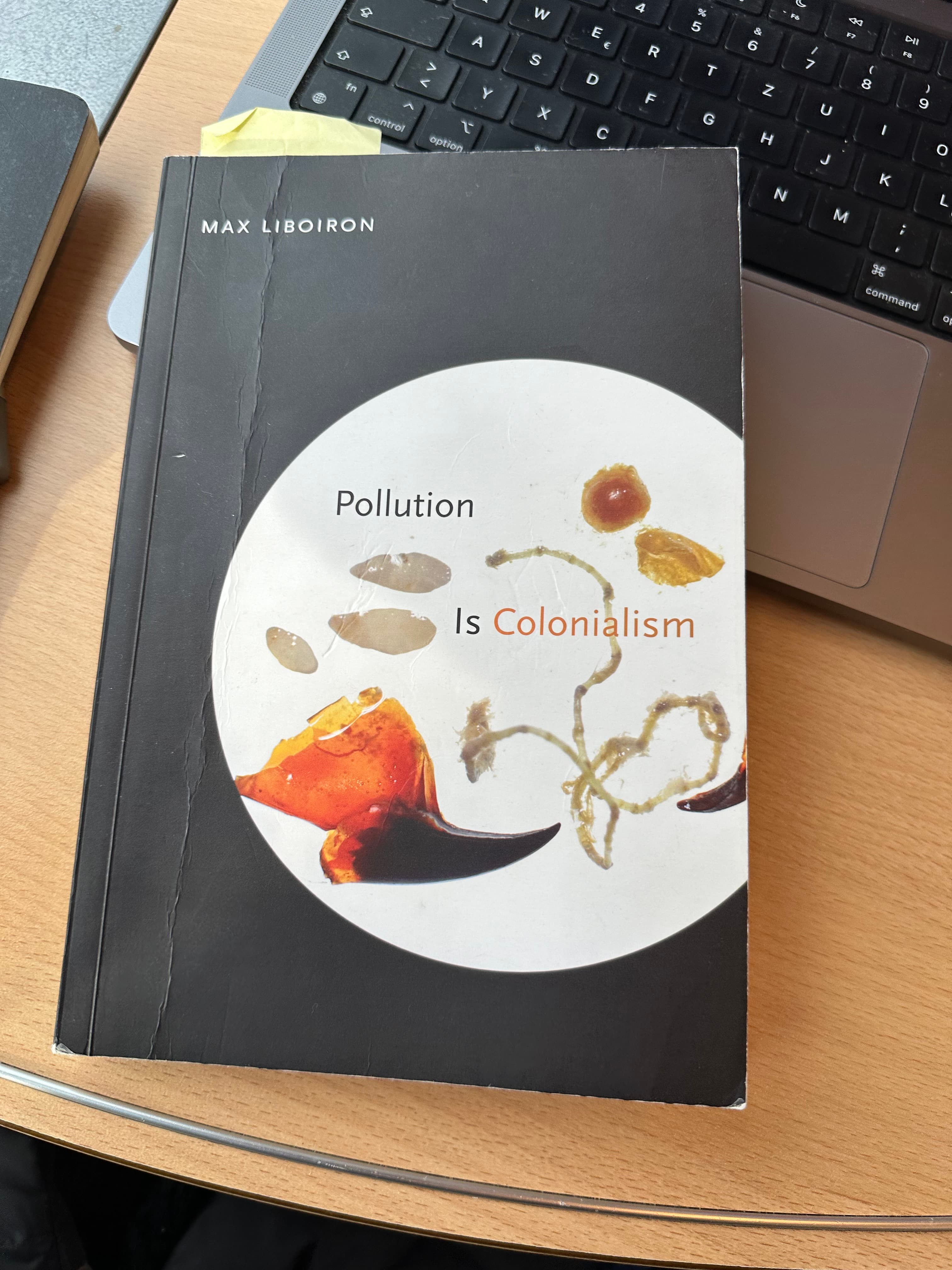 A book on the laptop. The book is Pollution is Colonialism by Max Liboiron.
