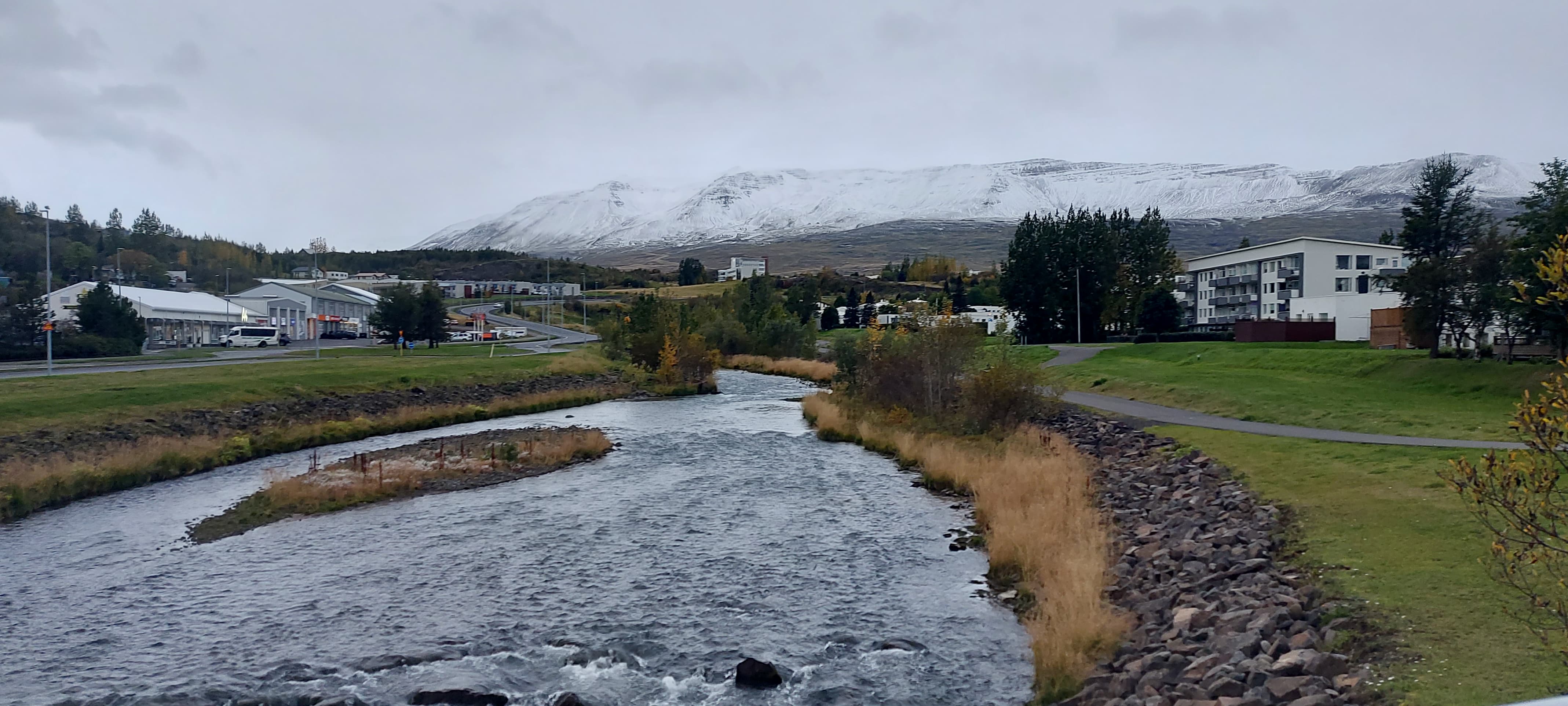 Akureyri landscape: a river, houses and a snowy mountain in the background.