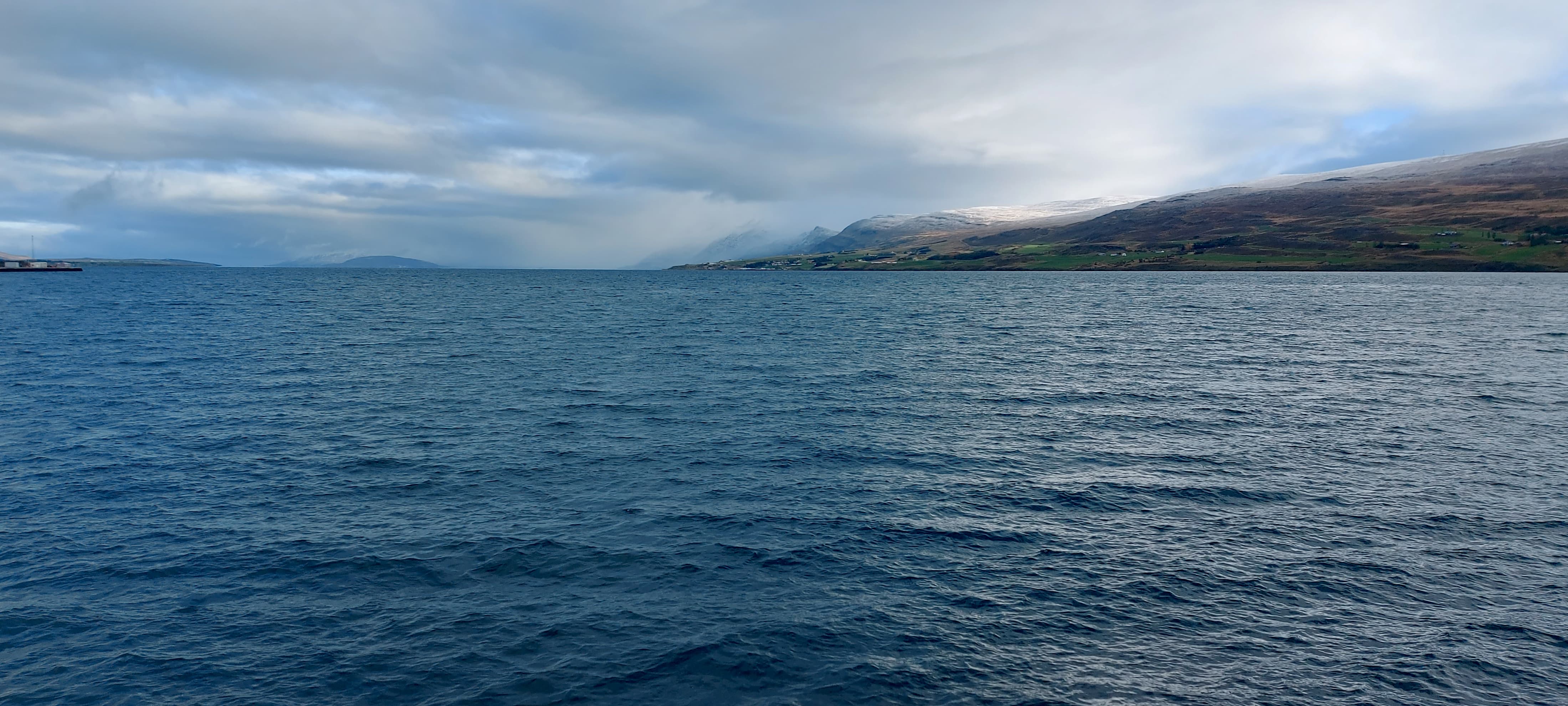 Sea with a snowy mountain in the background in Akureyri, Iceland.