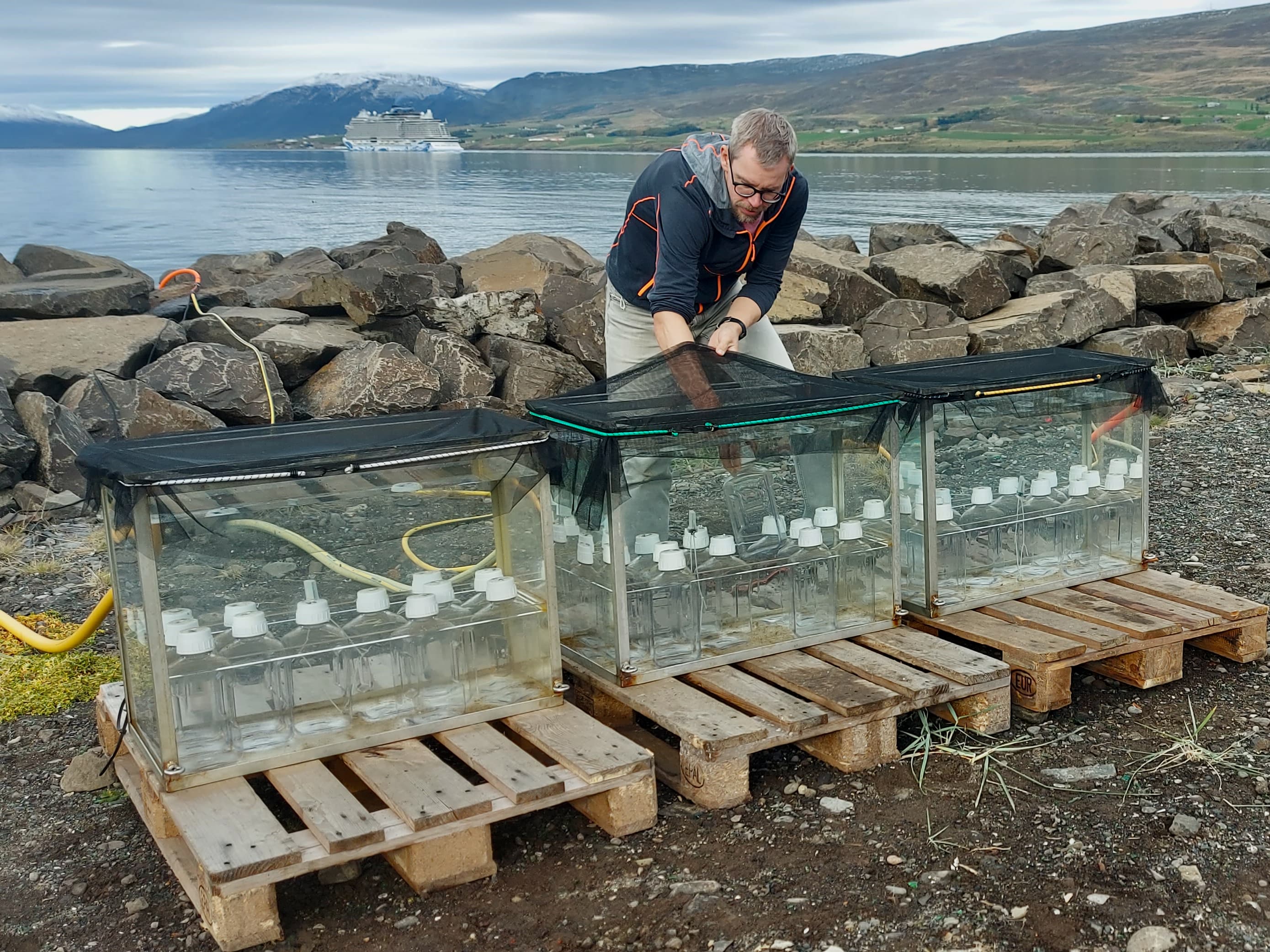 On a beach in Akureyri, Dennis Booge places bottles of sample water on large tanks.
