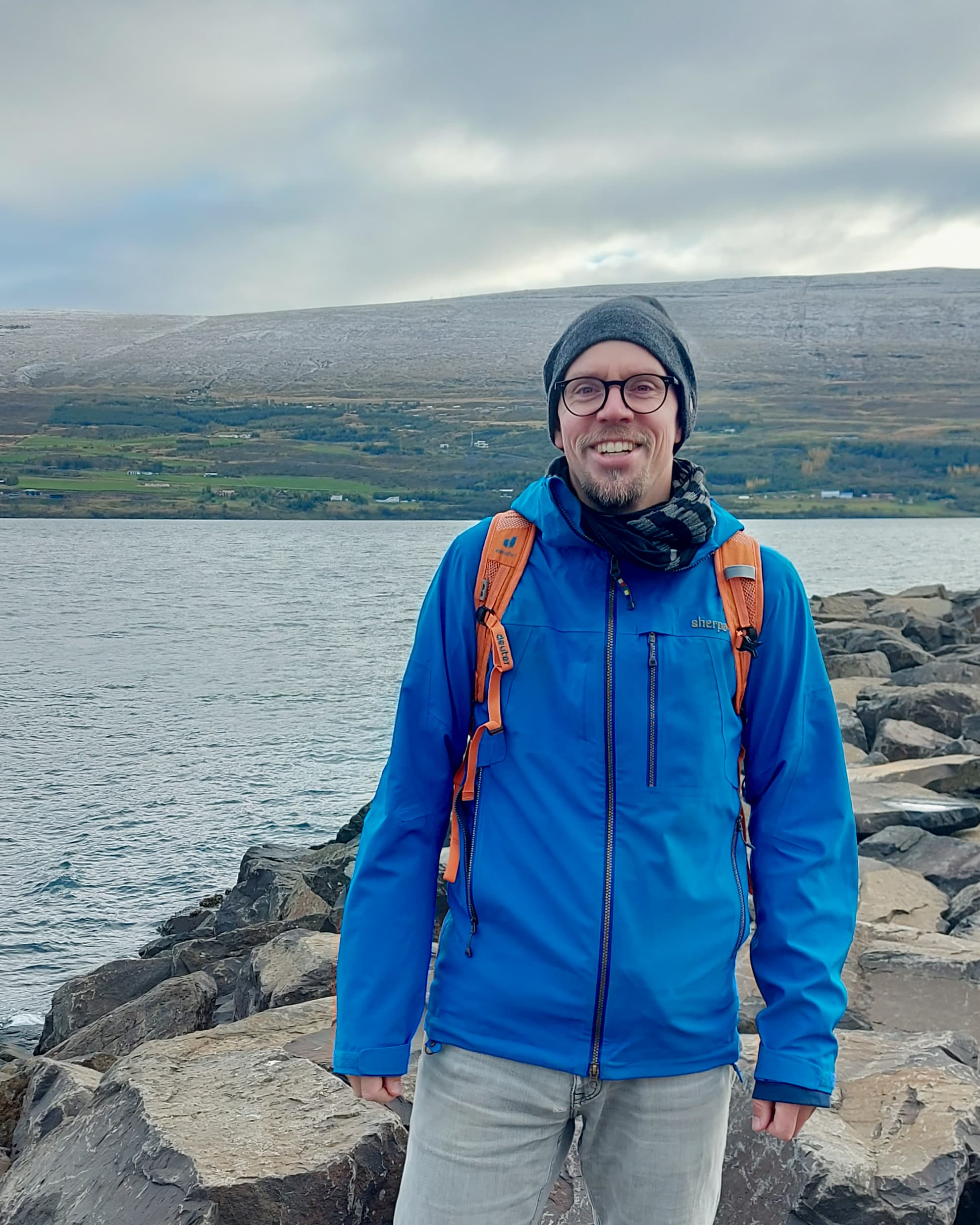 Dennis Booge poses in outdoor clothing in front of a fjord in Iceland.