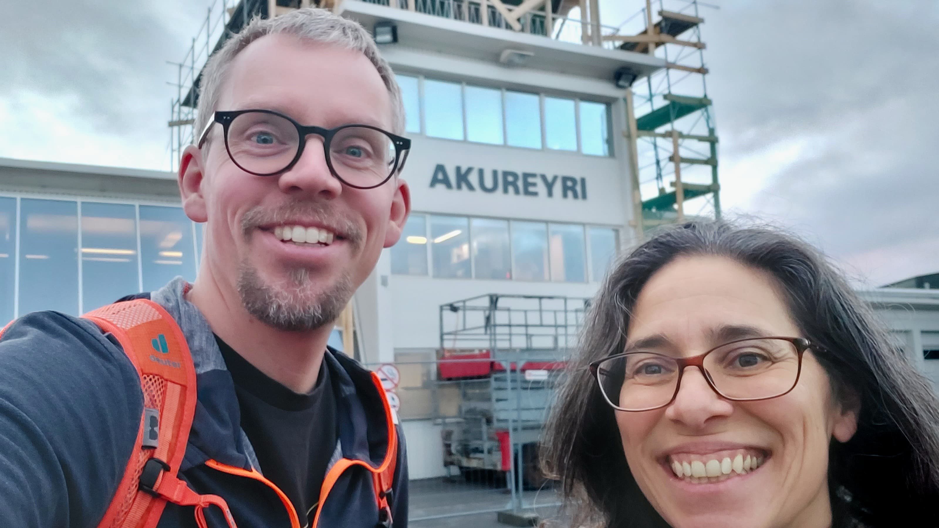 A selfie photo of Dennis Booge and Christa Marandino in front of a building that says Akureyri.
