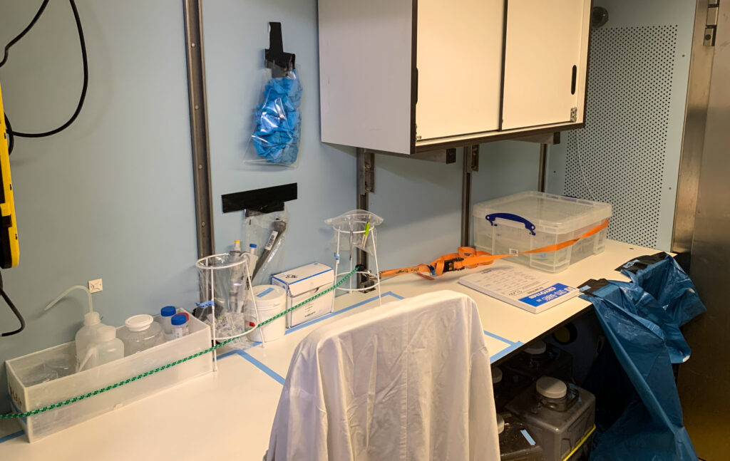 Laboratory bench on a research vessel with containers, tubing, and sampling tools.