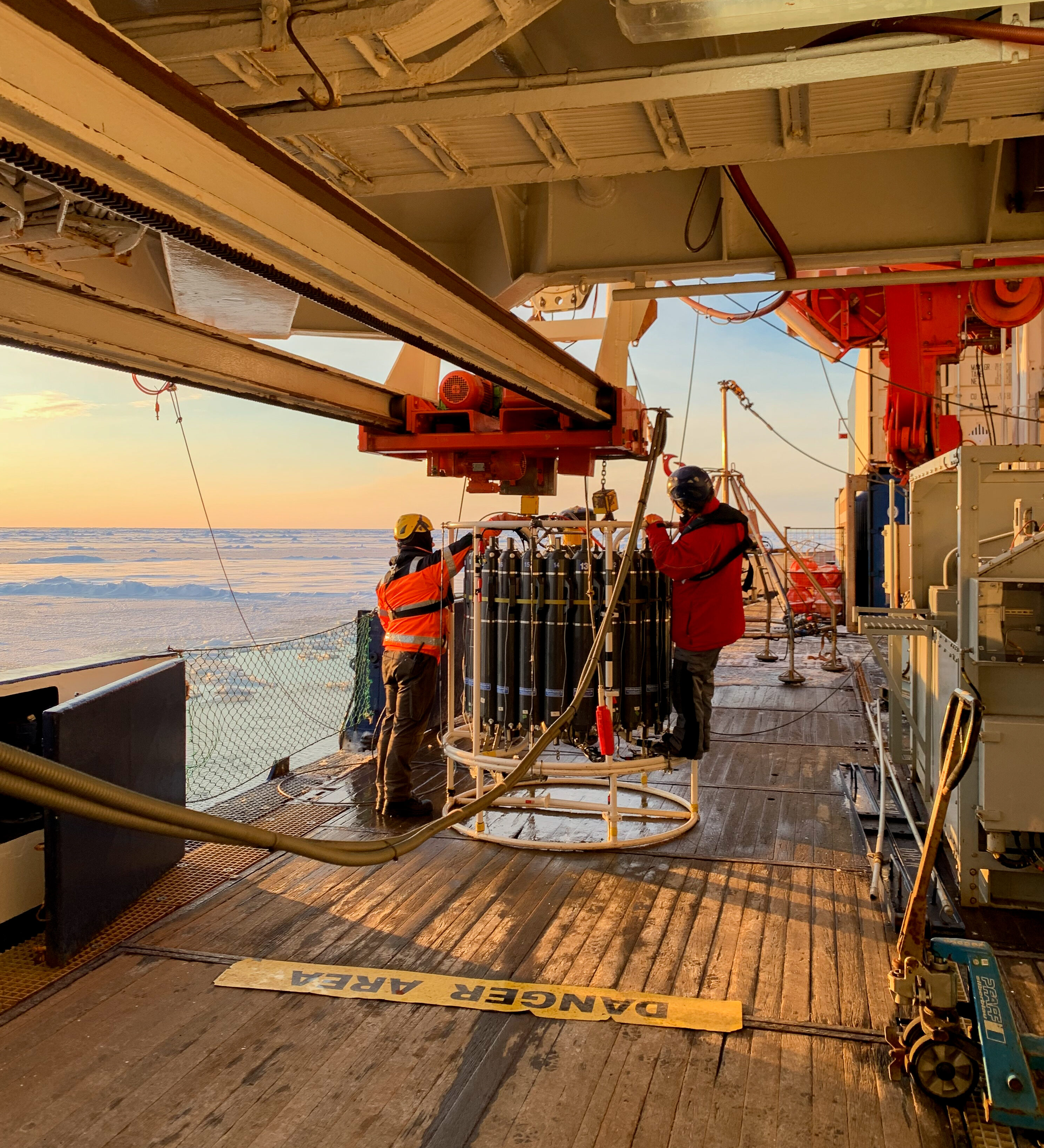Researchers preparing oceanographic sampling equipment on the deck of an icebreaker.