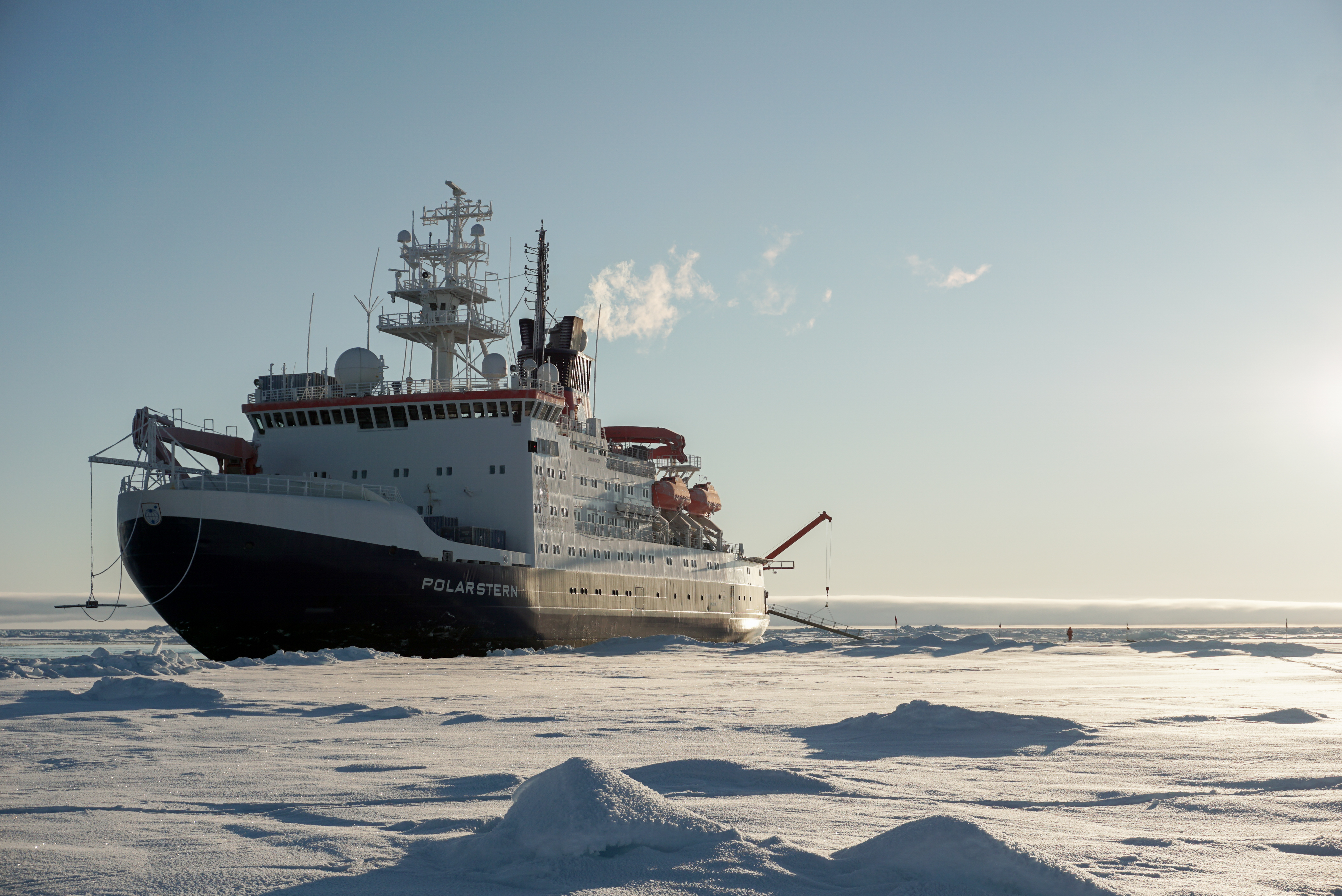A picture of the Polarstern research vessel in a snowy landscape. The vessel is white and red with a dark blue bottom.