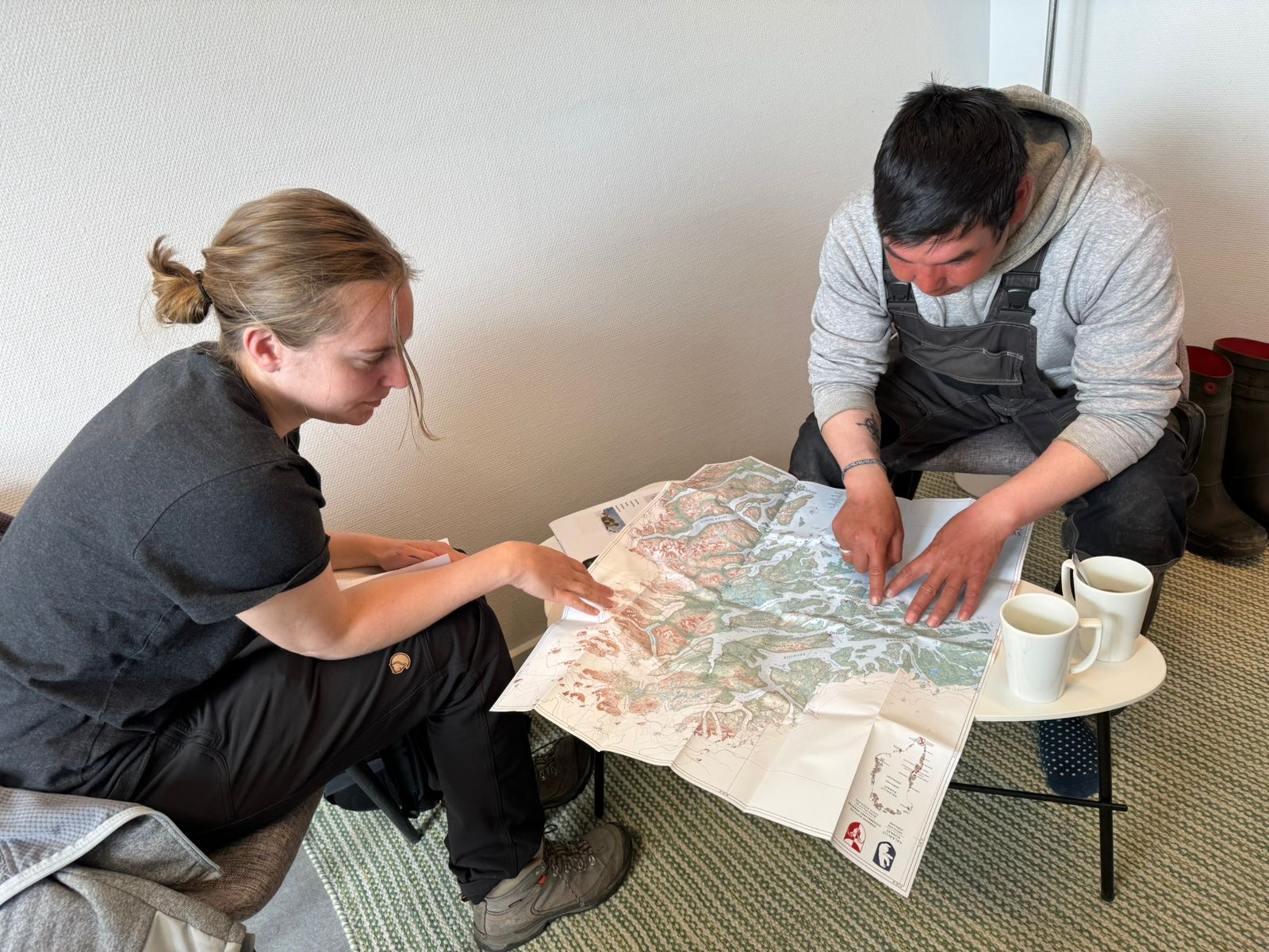 Two people sitting across from each other at a table, studying a map.