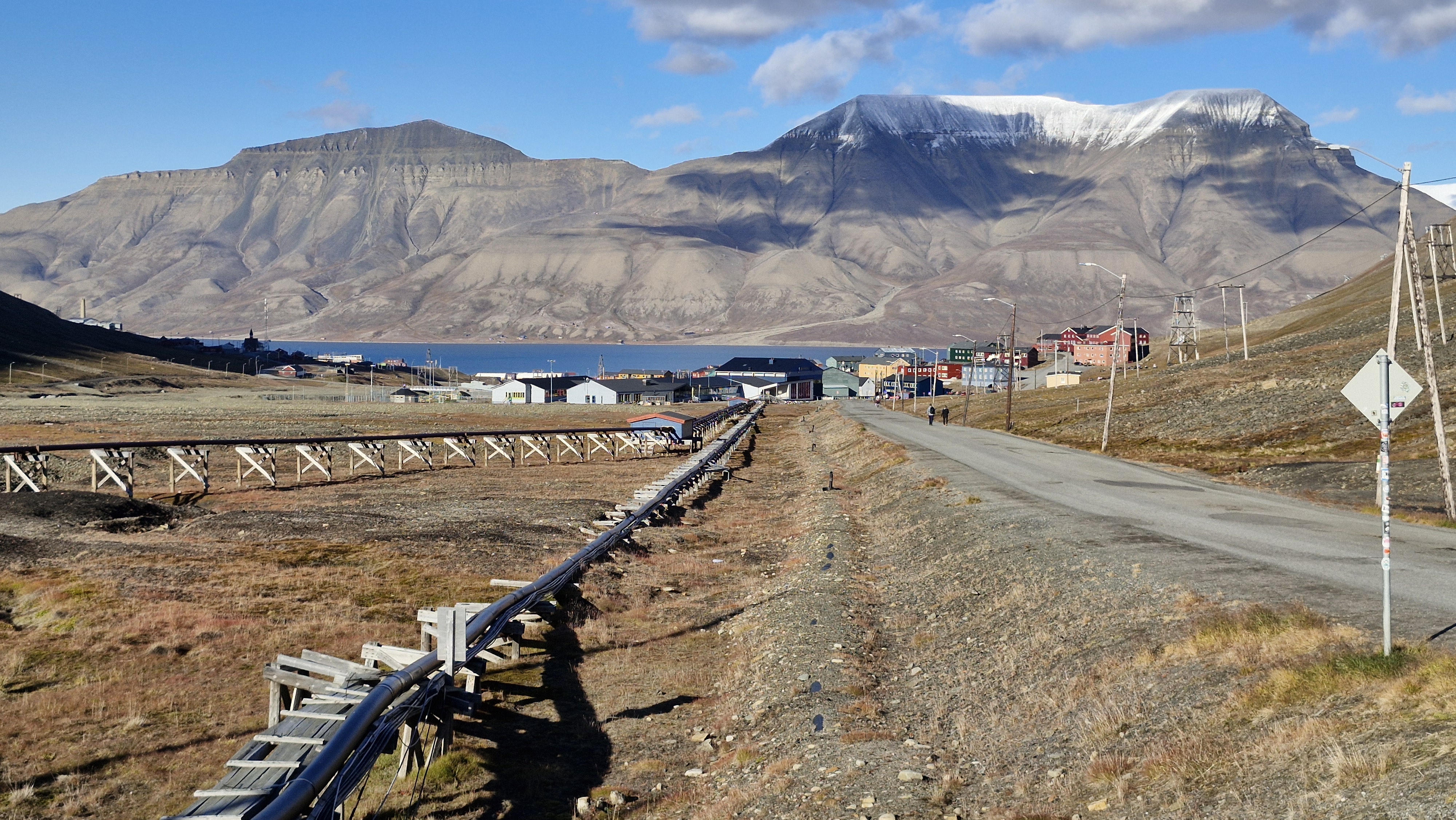 Mountain landscape, houses in the distance, water pipes running on the ground.
